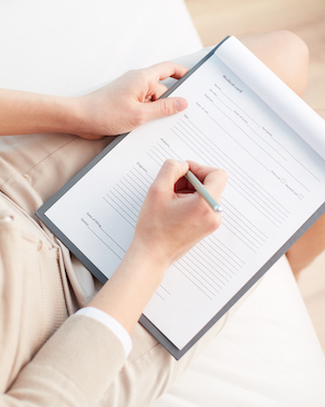 Elger Dental | Person filling out a form on a clipboard while seated